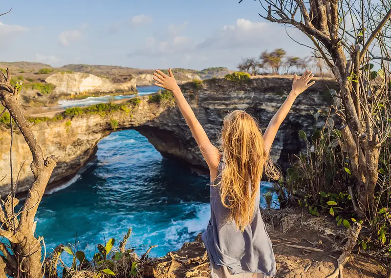 Tourist overlooking the natural rock arch at Broken Beach in Nusa Penida Bali